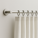 Aluminium curtain rod with white curtains hanging on metal rings.