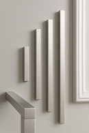 Vertical aluminum rectangular bars of varying lengths mounted on a light-colored wall.