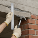 Worker fitting aluminum trim on concrete edge with hammer