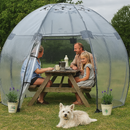 Family enjoying an outdoor meal inside a clear dome tent with their dog.