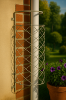 Metal drainpipe trellis on brick wall with purple flowers nearby.