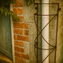 Rustic twisted metal drainpipe cover on brick and stone wall.