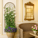 Elegant corner with a wicker seat, gold mirror, floral trellis, and vibrant potted flowers.