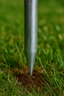 Pointed steel tubing inserted into garden soil for secure anchoring.
