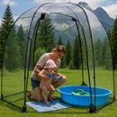 Mother and baby playing in a clear dome tent with a kiddie pool on grass.
