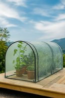 Portable mesh grower tunnel on wooden deck with potted plants.