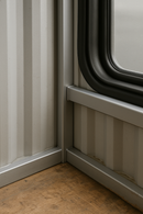 Corner view of metal wall framing around a window with a rubber seal.